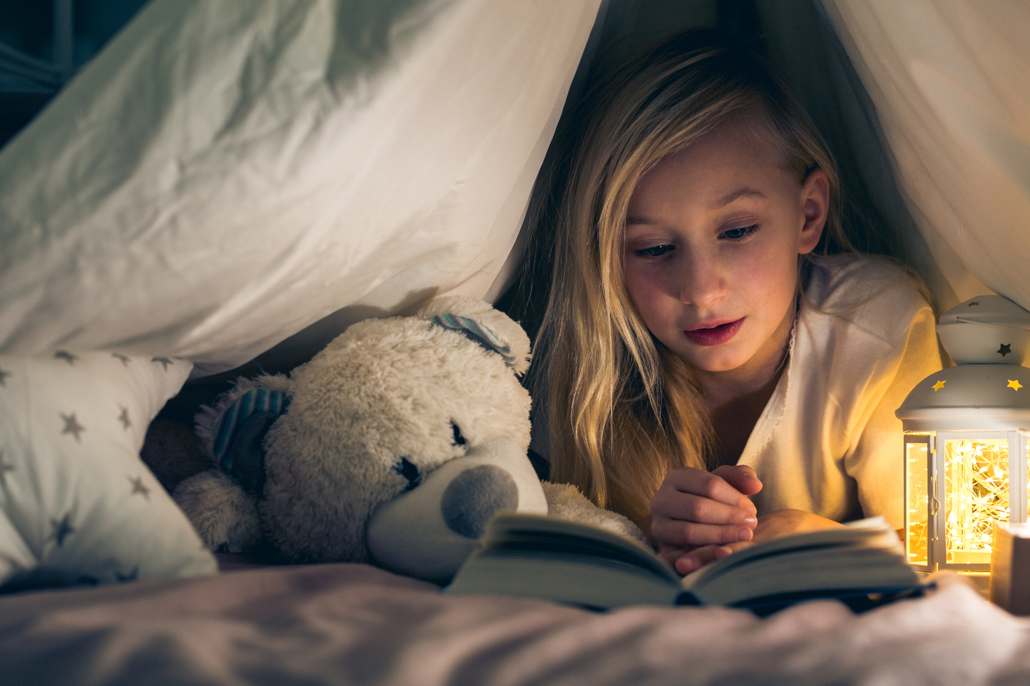 Un enfant lit un livre au lit la veille de Noël