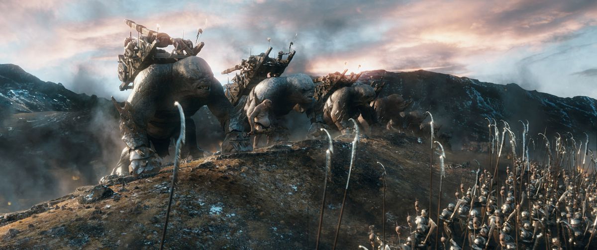 Une ligne d'armes de siège montées sur des trolls franchit une colline, affrontant une autre armée dans Le Hobbit : La Bataille des Cinq Armées.
