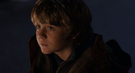 Ty Simpkins sitting outside with a sad expression in Iron Man 3.