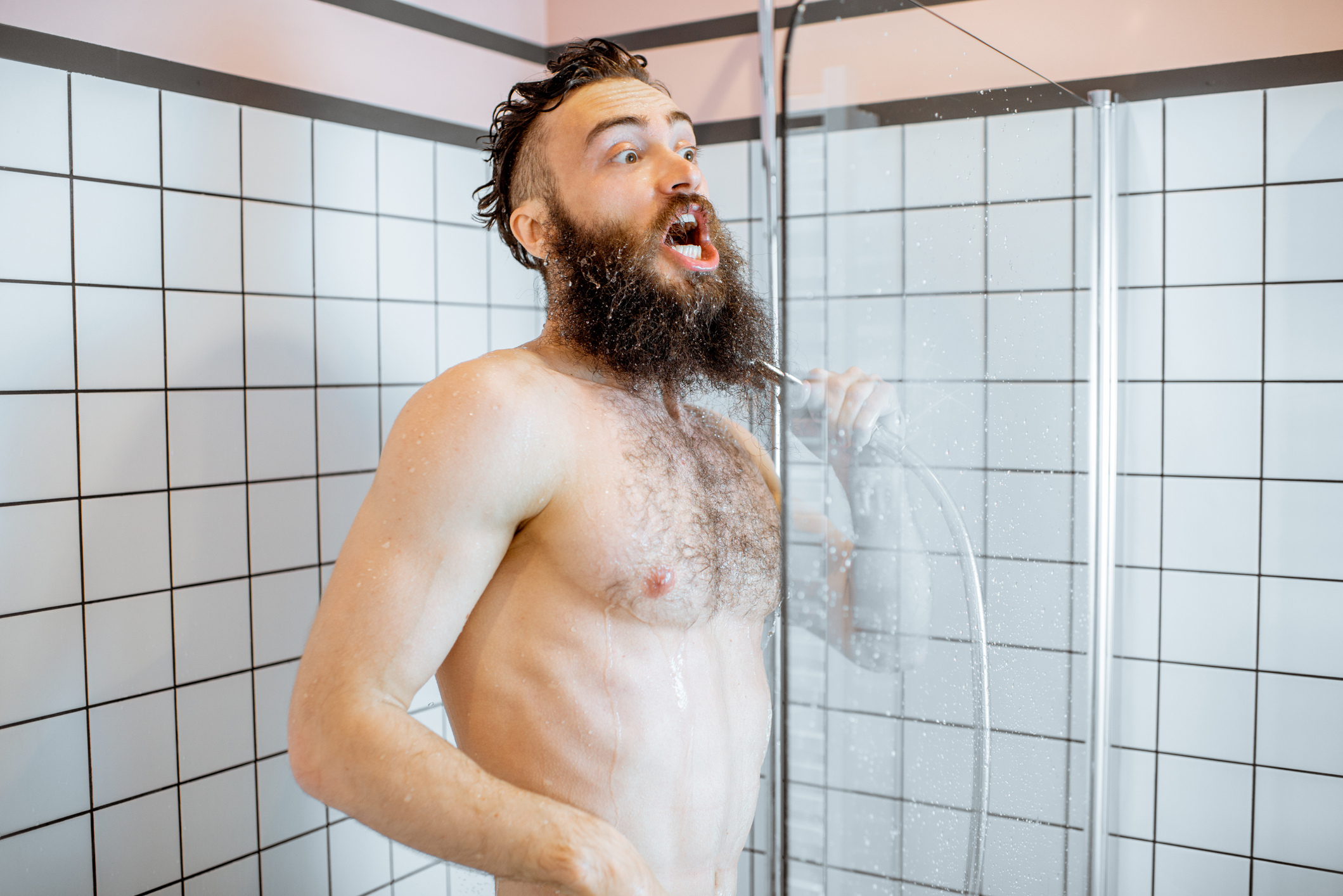 Un homme ouvre la bouche sous le choc en prenant une douche froide