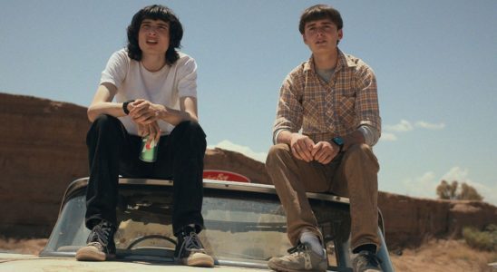 Mike and Will sitting on top of a car on Stranger Things looking into the distance.