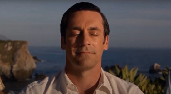 Jon Hamm sits in nature with a smile in Mad Men.