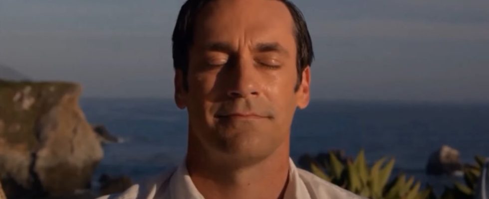 Jon Hamm sits in nature with a smile in Mad Men.