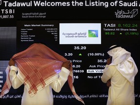 Les responsables de la bourse saoudienne regardent l'écran boursier sur la bourse de Riyad, en Arabie Saoudite.