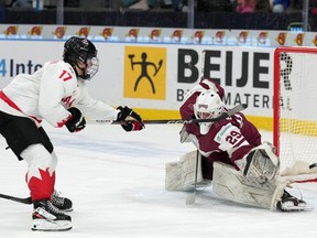 Macklin Celebrini du Canada marque sur le gardien letton Linards Feldbergs lors de la ronde préliminaire de deuxième période du Championnat mondial de hockey junior de l'IIHF à Göteborg, en Suède, le mercredi 27 décembre 2023.