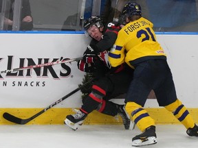 Le Suédois Zeb Forsfjall (21 ans) pousse Owen Beck (8 ans) du Canada sur les planches du Championnat mondial de hockey junior de l'IIHF à Göteborg, en Suède, le vendredi 29 décembre 2023.