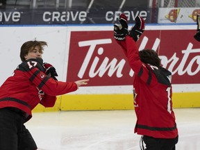 Macklin Celebrini (17 ans) du Canada lance un gant à Fraser Minten (12 ans) après la photo d'équipe au Championnat mondial de hockey junior de l'IIHF à Göteborg, en Suède, le jeudi 28 décembre 2023.