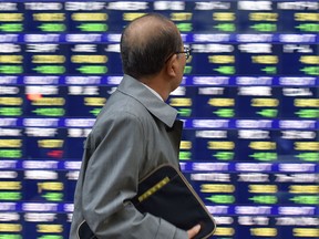 Un piéton regarde un panneau de cotation affichant l'indice clé Nikkei de la Bourse de Tokyo à Tokyo.