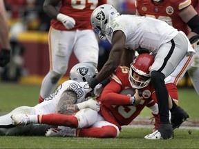 Le quart-arrière des Chiefs de Kansas City Patrick Mahomes (15) est arrêté par l'ailier défensif des Raiders de Las Vegas Maxx Crosby (98) et le secondeur Divine Deablo (5) pendant la seconde moitié d'un match de football de la NFL, le lundi 25 décembre 2023, à Kansas City, Mo.
