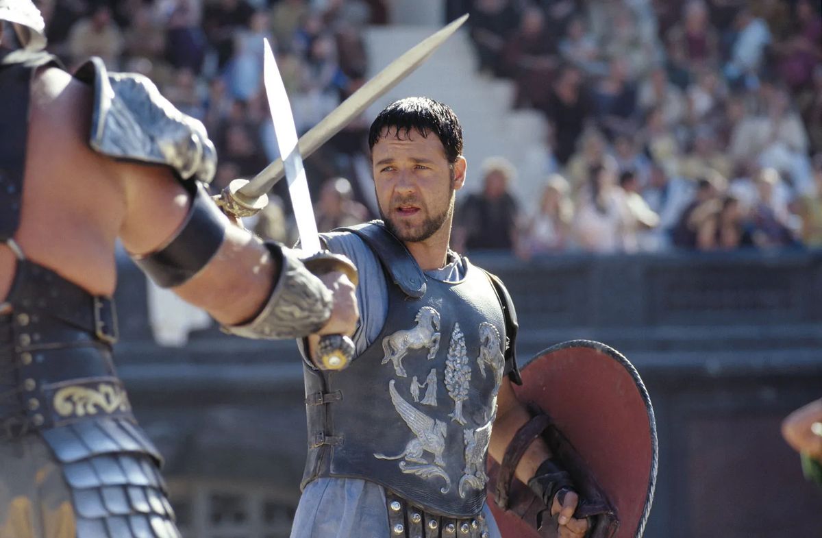Russell Crowe dans le rôle du général Maximus Decimus Meridius croisant le fer avec un gladiateur dans Gladiator.