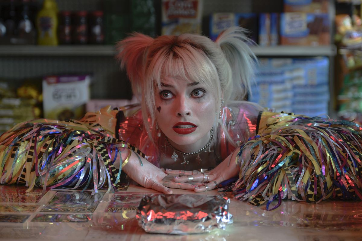Margot Robbie pose ses bras sur un comptoir de charcuterie et regarde d'un air suppliant son sandwich au petit-déjeuner dans le rôle d'Harley Quinn dans Birds of Prey.