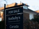 Une pancarte de vente immobilière se trouve devant une maison dans un quartier de l’ouest de Toronto.