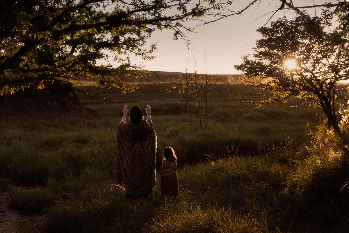 Une belle photo au coucher du soleil de Mollie (Lily Gladstone) priant le soleil dans un champ avec sa fille