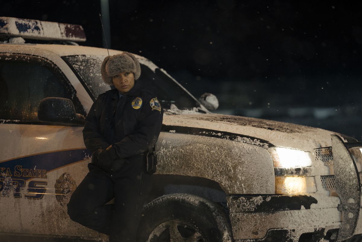 Kali Reis s'appuie contre un SUV de flic dans une parka et un chapeau de fourrure dans le rôle de l'officier Navarro dans True Detective : Night Country