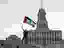 Un manifestant brandit un drapeau au sommet d'une arche de la place Nathan Phillips lors d'un rassemblement en soutien à la Palestine à Toronto, le samedi 4 novembre 2023. Des manifestants pro-palestiniens ont perturbé la fête de patinage annuelle du maire à la place Nathan Phillips le dimanche 4 janvier. 7, 2024.