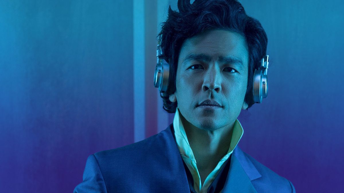 Photo d'un homme portant des écouteurs debout sur un fond bleu