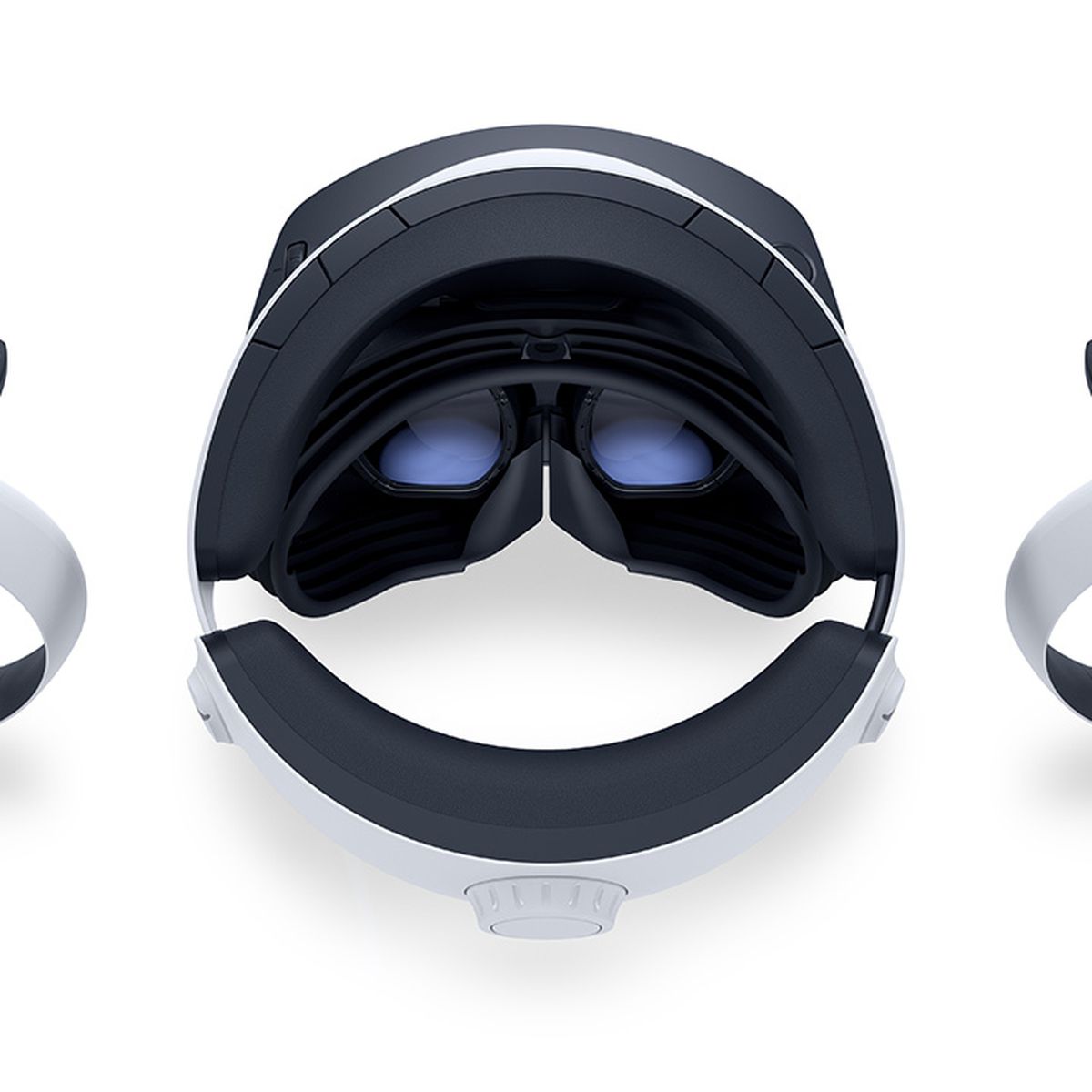 Le casque PSVR 2, vu du dessus, posé sur une surface blanche, flanqué des deux contrôleurs VR2 Sense