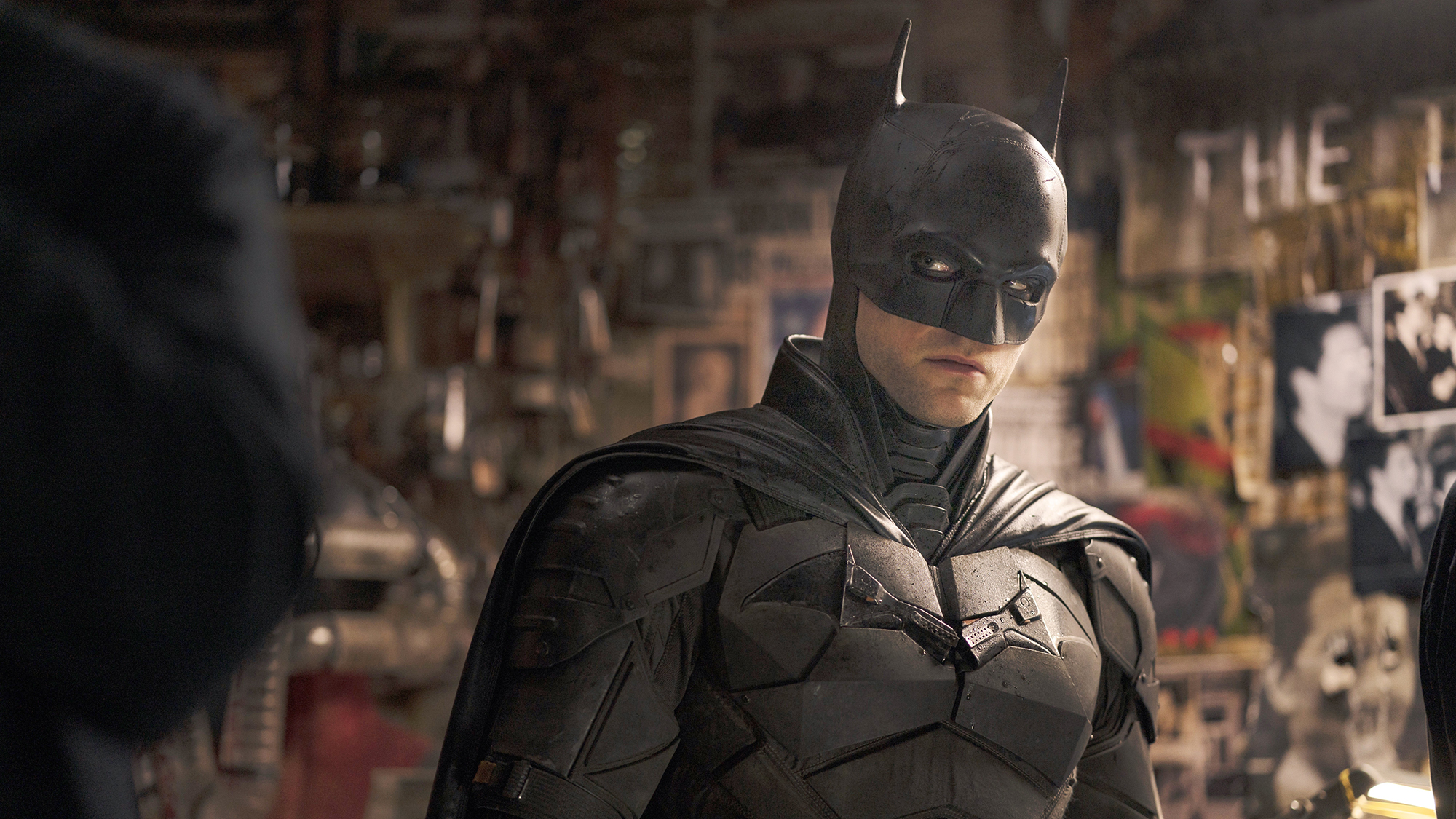 Robert Pattinson dans le rôle de Batman, dans une pièce remplie d'images et de preuves probables du film The Batman