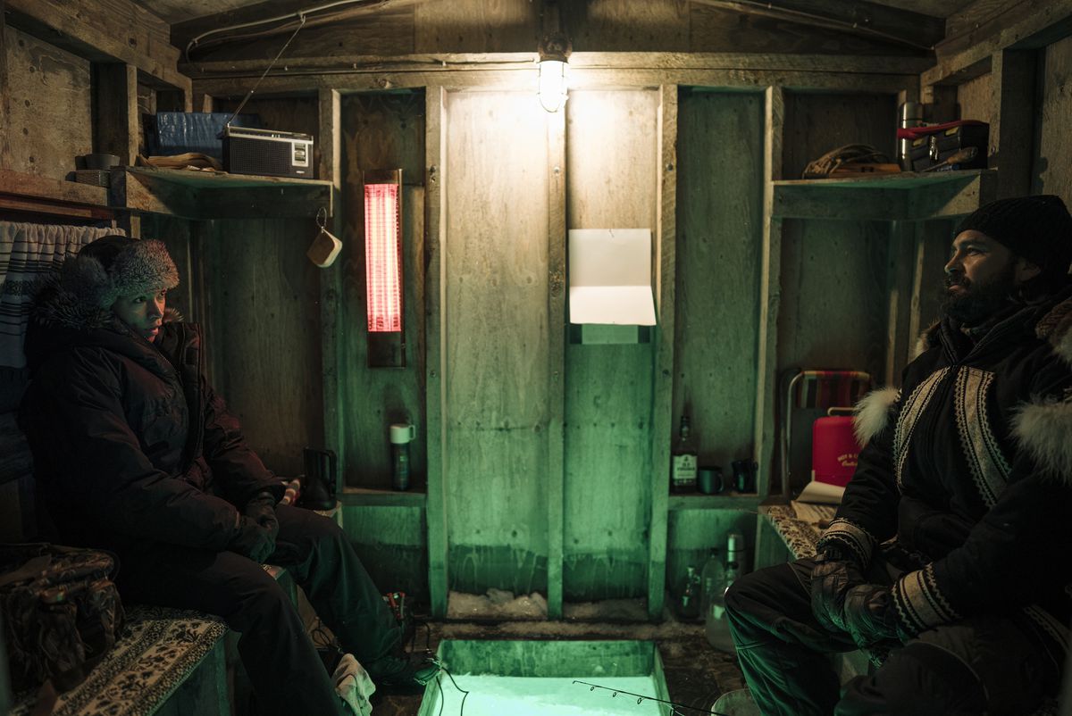 Navarro (Kali Reis) assis avec Qavvik (Joel Montgrand) dans sa cabane de pêcheur, lui parlant de sa mère