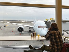 Un voyageur regarde un avion d'Air Canada alors qu'il attend son vol à l'aéroport international Pierre Elliott Trudeau de Montréal, le vendredi 23 décembre 2023.