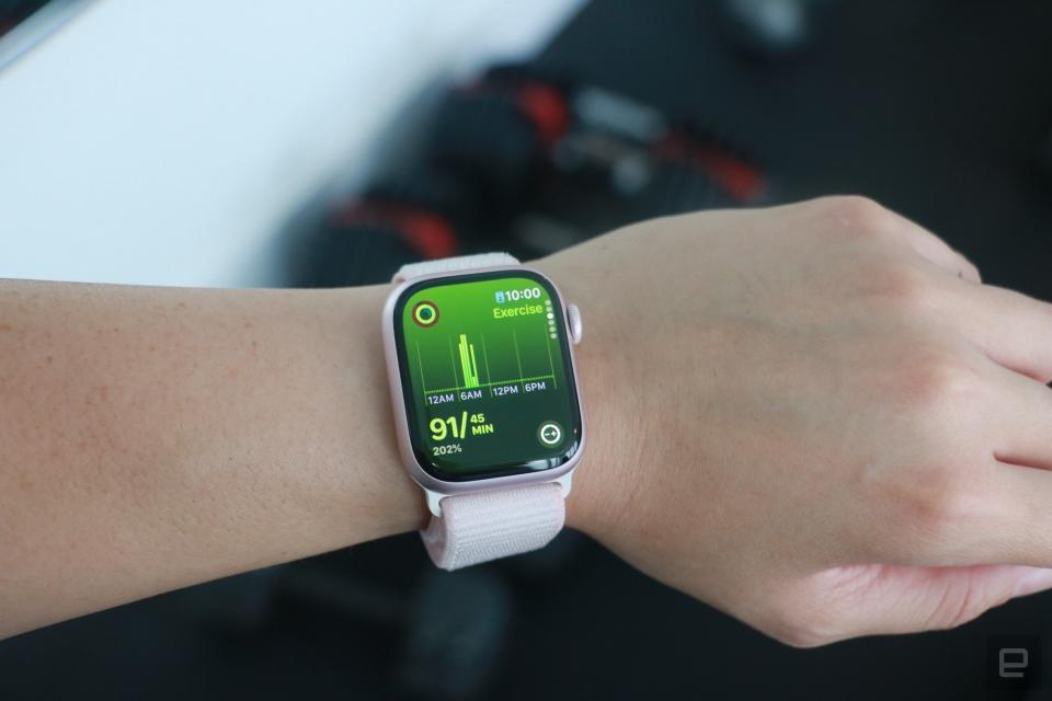 L'Apple Watch Series 9 au poignet d'une personne devant un équipement de gym, affichant la page Exercice de l'application Move Rings.