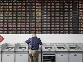 Un investisseur se tient devant un terminal commercial à Shanghai, en Chine