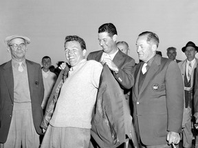 DOSSIER - Jack Burke Jr. est aidé par Cary Middlecoff alors qu'il enfile le manteau traditionnel après avoir remporté le 20e tournoi de golf Masters au parcours de golf national d'Augusta, en Géorgie, le 8 avril 1956. Jack Burke Jr., le plus vieux vivant Le champion des Masters qui a réalisé le plus grand retour de tous les temps à Augusta National pour l'un de ses deux majors, est décédé vendredi matin 19 janvier 2024 à Houston.  Il avait 100 ans. (AP Photo/Fichier)