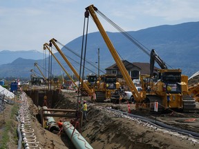 Des travailleurs posent des conduites pendant la construction de l’agrandissement du pipeline Trans Mountain