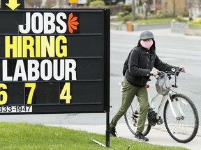 Une femme regarde une affiche d'offre d'emploi, à Toronto, le mercredi 29 avril 2020.