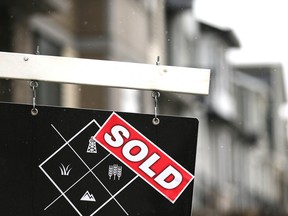 Une enseigne vendue à l'extérieur d'une maison à Calgary.  Les économistes s'attendent à ce que le marché immobilier se redresse cette année alors que la Banque du Canada commence à réduire les taux d'intérêt.