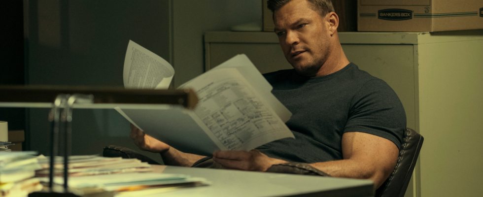 Jack Reacher (Alan Ritchson) sits at a desk combing through files in Prime Video's Reacher