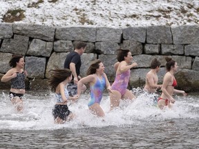 Des gens courent dans les eaux glaciales du bras nord-ouest, au large de l'océan Atlantique, à Halifax, le jour du Nouvel An, le lundi 1er janvier 2024.