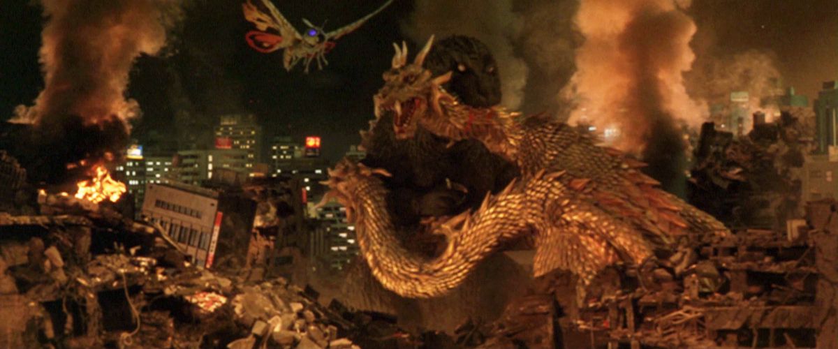 Godzilla mordant le cou du roi Ghidorah avec une ville en ruine en arrière-plan et Mothra volant vers eux.