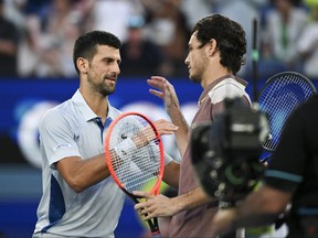 Novak Djokovic (L), de Serbie, serre la main de Taylor Fritz, des États-Unis, après la fin de leur match quart de finale masculin.