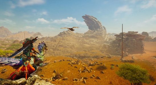 Image of a traveler in monster-like armor riding a bird creature through a rocky desert in Monster Hunter Wilds.