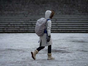 Une personne emmitouflée se promène pendant une brève chute de neige à Vancouver le jeudi 11 janvier 2024.