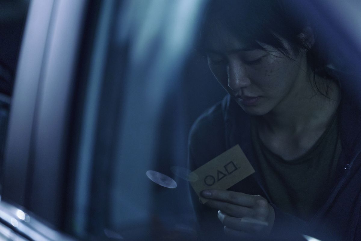 Un nouveau personnage anonyme de Squid Game (Park Gyu-young) tenant une carte de visite l'invitant au jeu