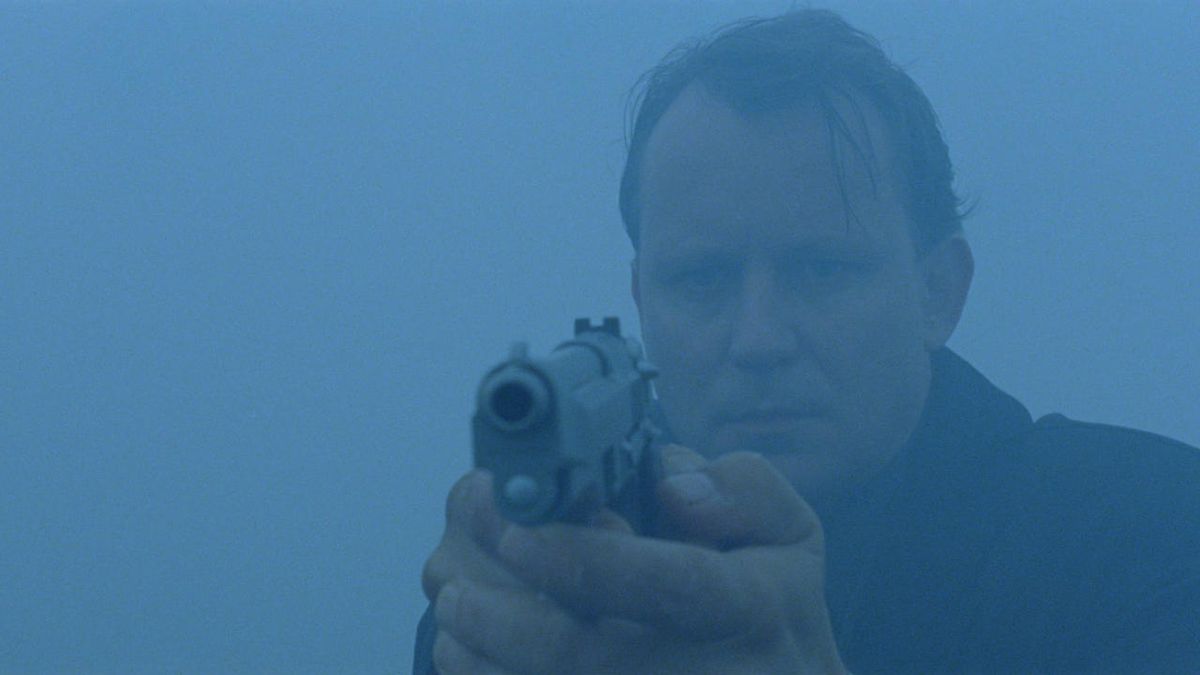 Plan moyen d'un homme tenant un pistolet entouré de brouillard.