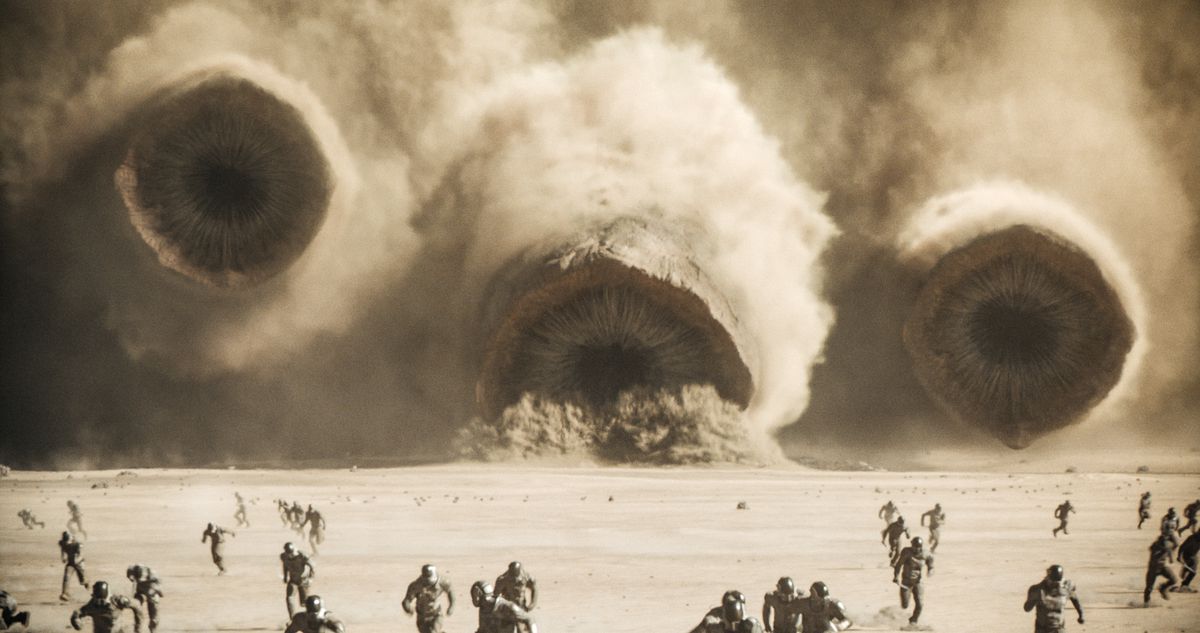 Les vers des sables d'Arrakis émergent d'une tempête dans Dune : deuxième partie avec des soldats devant eux