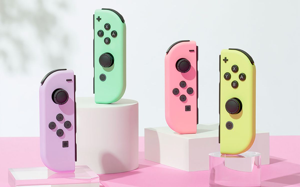 Quatre Joy-Cons Nintendo Switch aux couleurs pastel debout sur des supports en acrylique blanc opaque et transparent