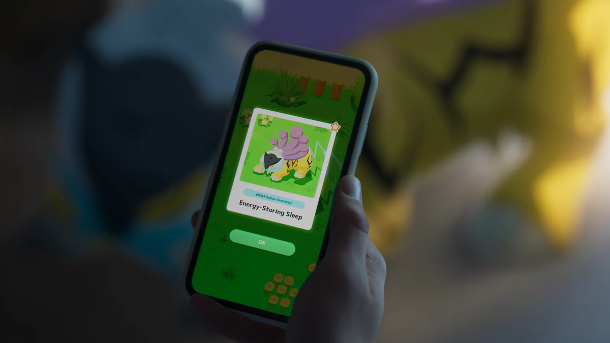 Photo d'une personne tenant un téléphone portable et jouant à Pokemon Sleep