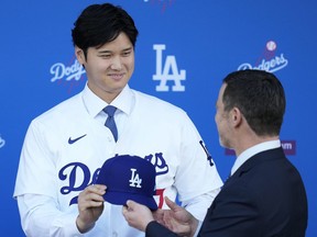 Shohei Ohtani des Dodgers de Los Angeles reçoit une casquette de baseball des mains du président des opérations baseball Andrew Friedman.