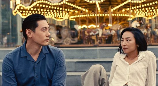 Teo Yoo and Greta Lee as Hae Sung and Na Young in front of a carousel in Past Lives
