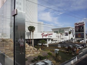Une personne, reflétée dans une vitre, marche près du Tropicana Las Vegas