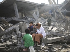 Les responsables américains affirment qu'ils tentent toujours de comprendre ce qui a poussé l'armée israélienne à arrêter les membres d'une famille canado-américaine dans la bande de Gaza.  Les Palestiniens sont assis devant les destructions causées par le bombardement israélien de la bande de Gaza à Rafah, le lundi 12 février 2024.