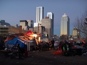 Un homme se prépare à déplacer ses affaires alors que la police et les équipes de nettoyage se préparent à démolir les campements de sans-abri à Edmonton le vendredi 29 décembre 2023.