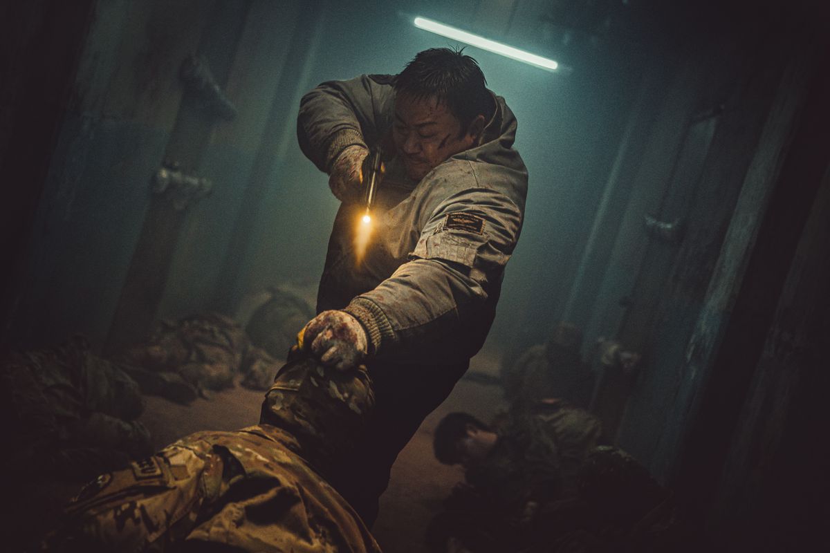 Ma Dong-seok tire avec un pistolet dans un couloir rempli de corps affalés dans Badland Hunters