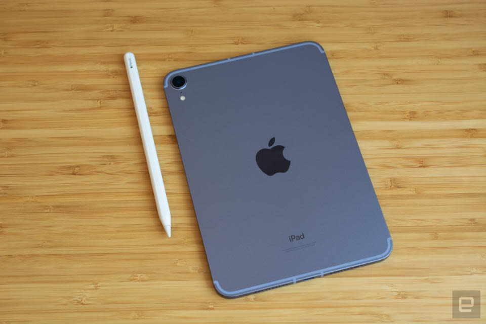 Photo de l'iPad mini de 6e génération posé sur une élégante table en bois, le dos (avec le logo Apple) tourné vers le haut.  Son Apple Pencil se trouve à sa gauche.