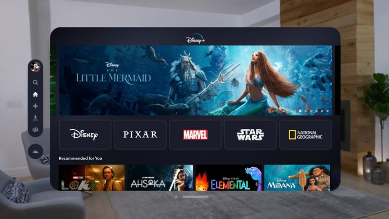 Image de l'application Disney+ pour VisionOS.  Une fenêtre flottante affiche le menu d'accueil du service dans un salon.