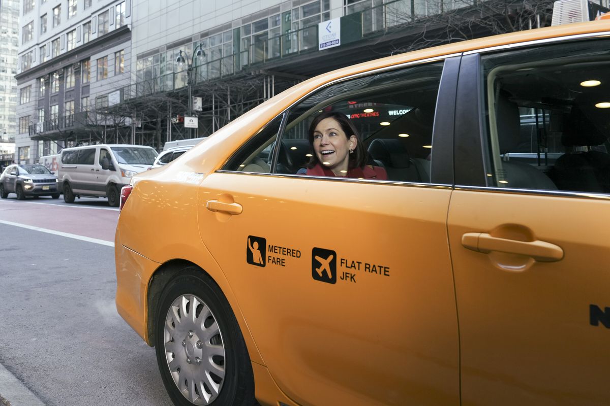 Elsbeth est assise à l'arrière d'un taxi, souriant par la fenêtre dans une photo d'Elsbeth